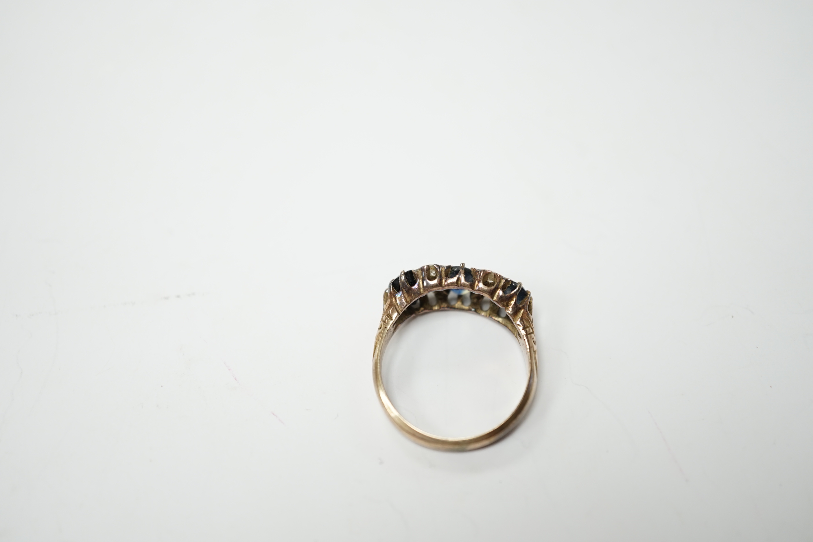 An early 20th century 18ct and graduated three stone sapphire set half hoop ring, with diamond chip spacers, size P, gross weight 3.8 grams.